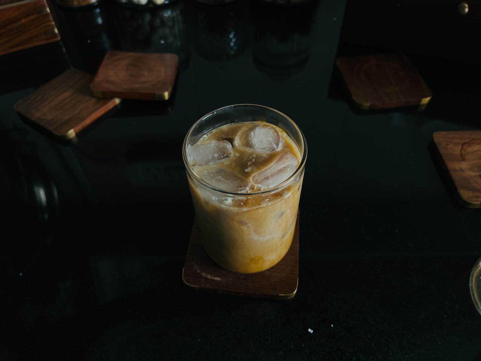 A glass of iced coffee on a wooden coaster, perfect for a refreshing break.