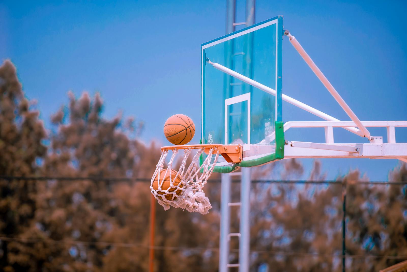 Basketball shot caught mid-air against a clear blue sky on an outdoor court.