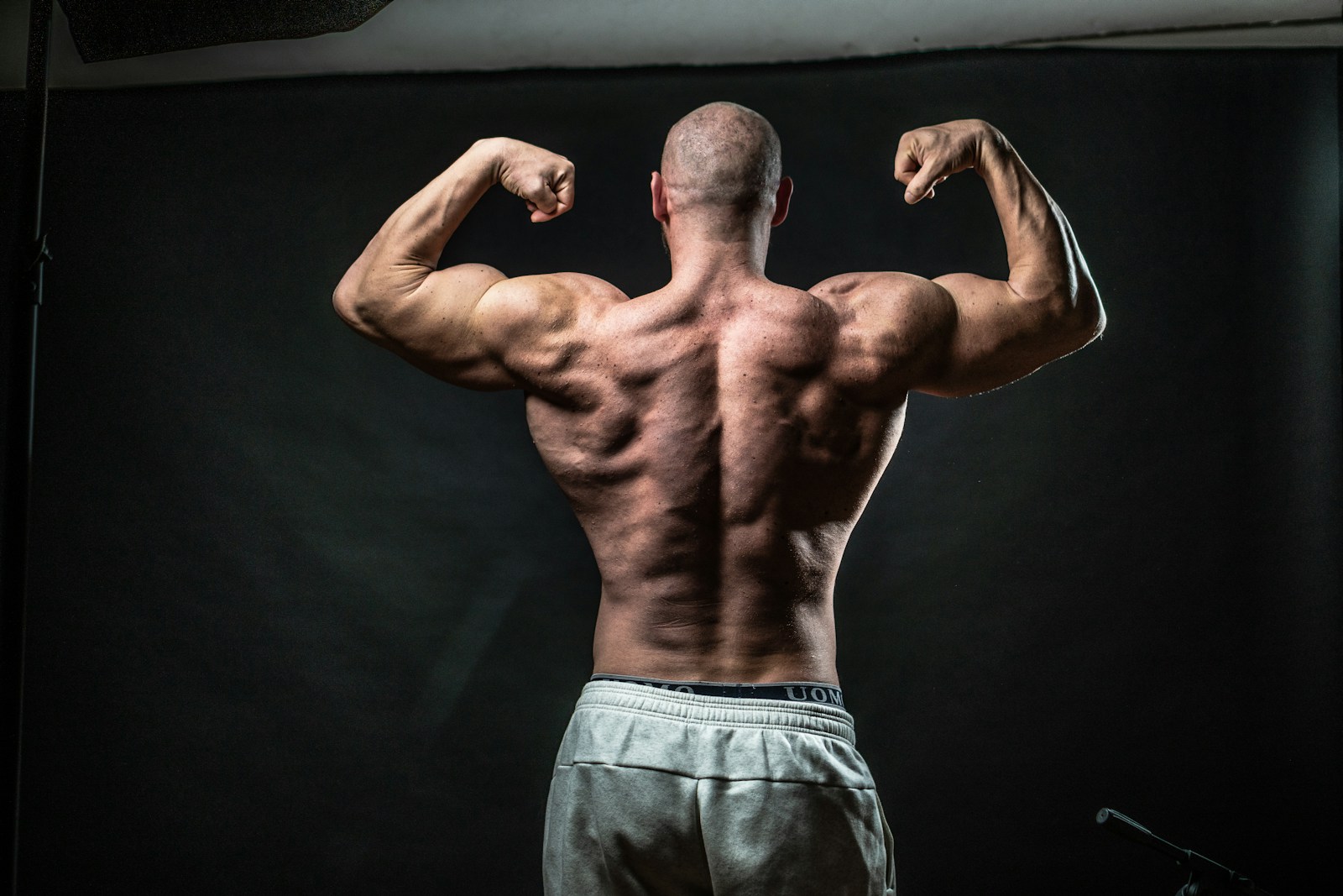 a man flexing his muscles in front of a black background