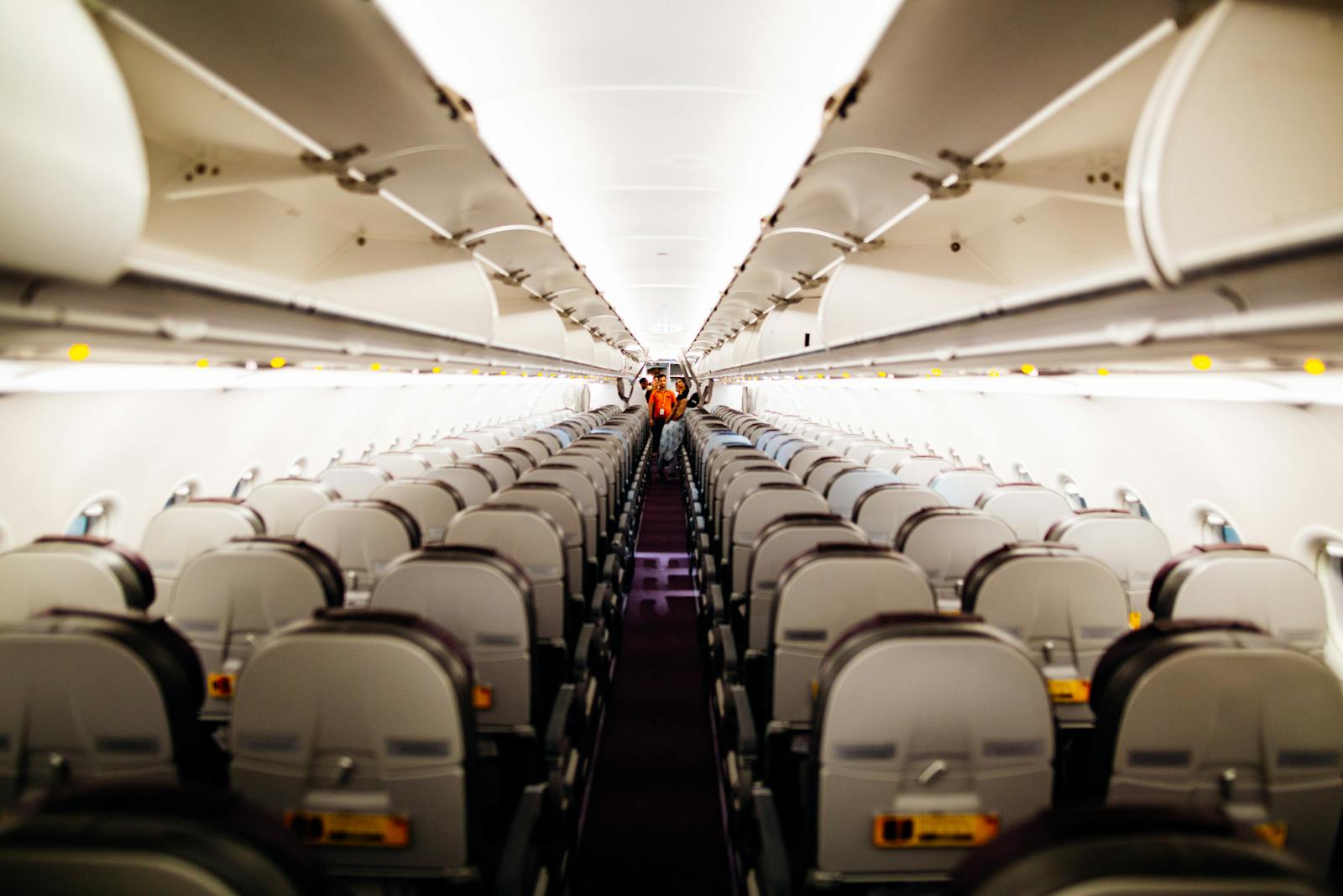 View of an empty airplane interior with aisle seats and overhead bins.