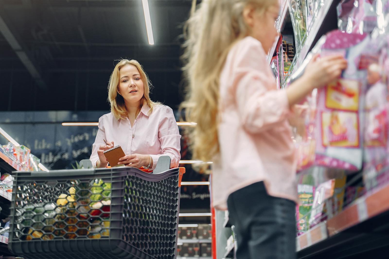 Mother and daughter shopping together in a supermarket, focused on selecting the right products.