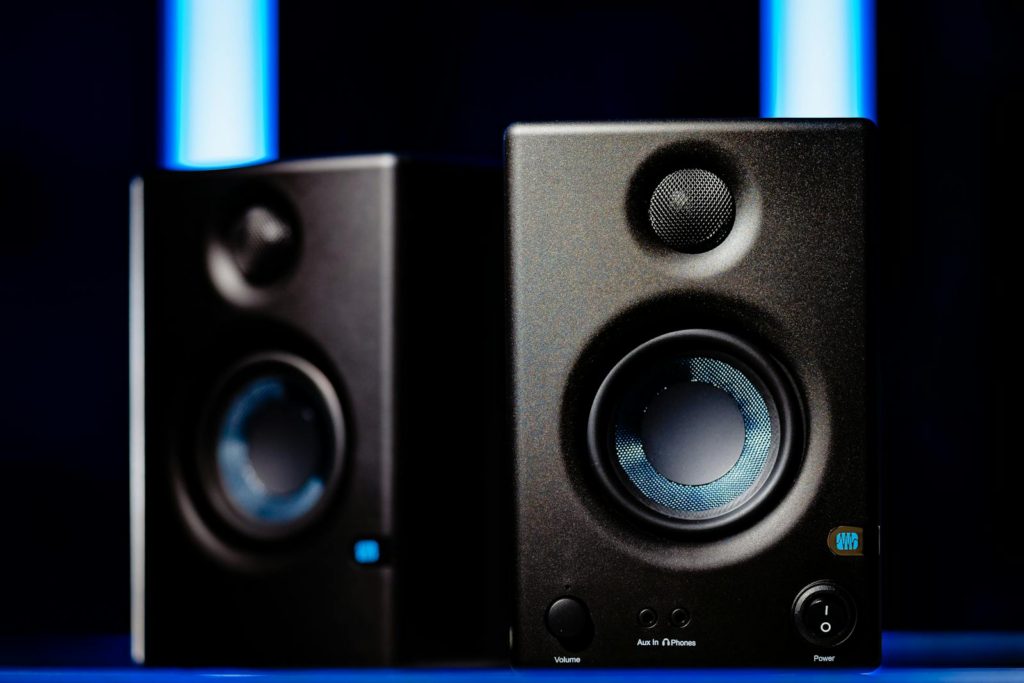 Close-up of modern black loudspeakers with blue accents in a studio setting.