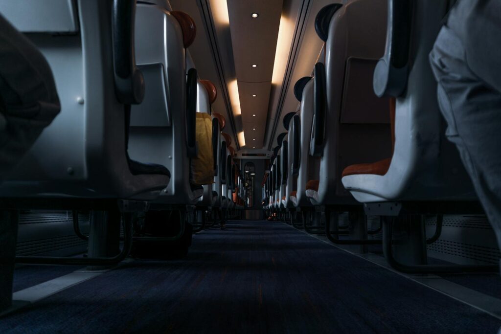 A perspective shot of a modern train's cabin aisle, featuring empty seats.