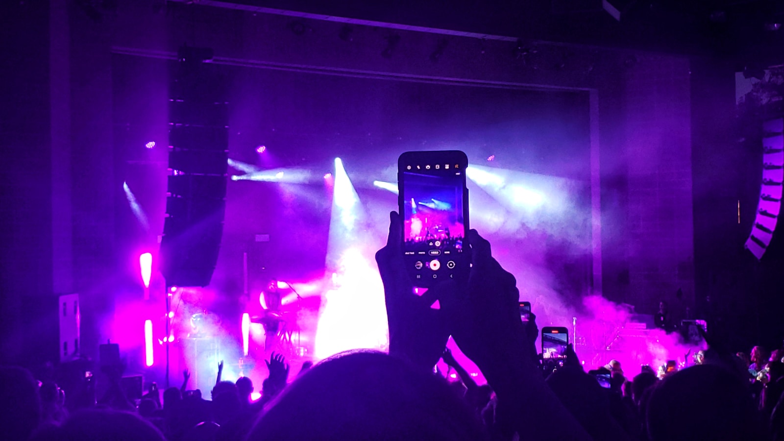 person taking photo of concert