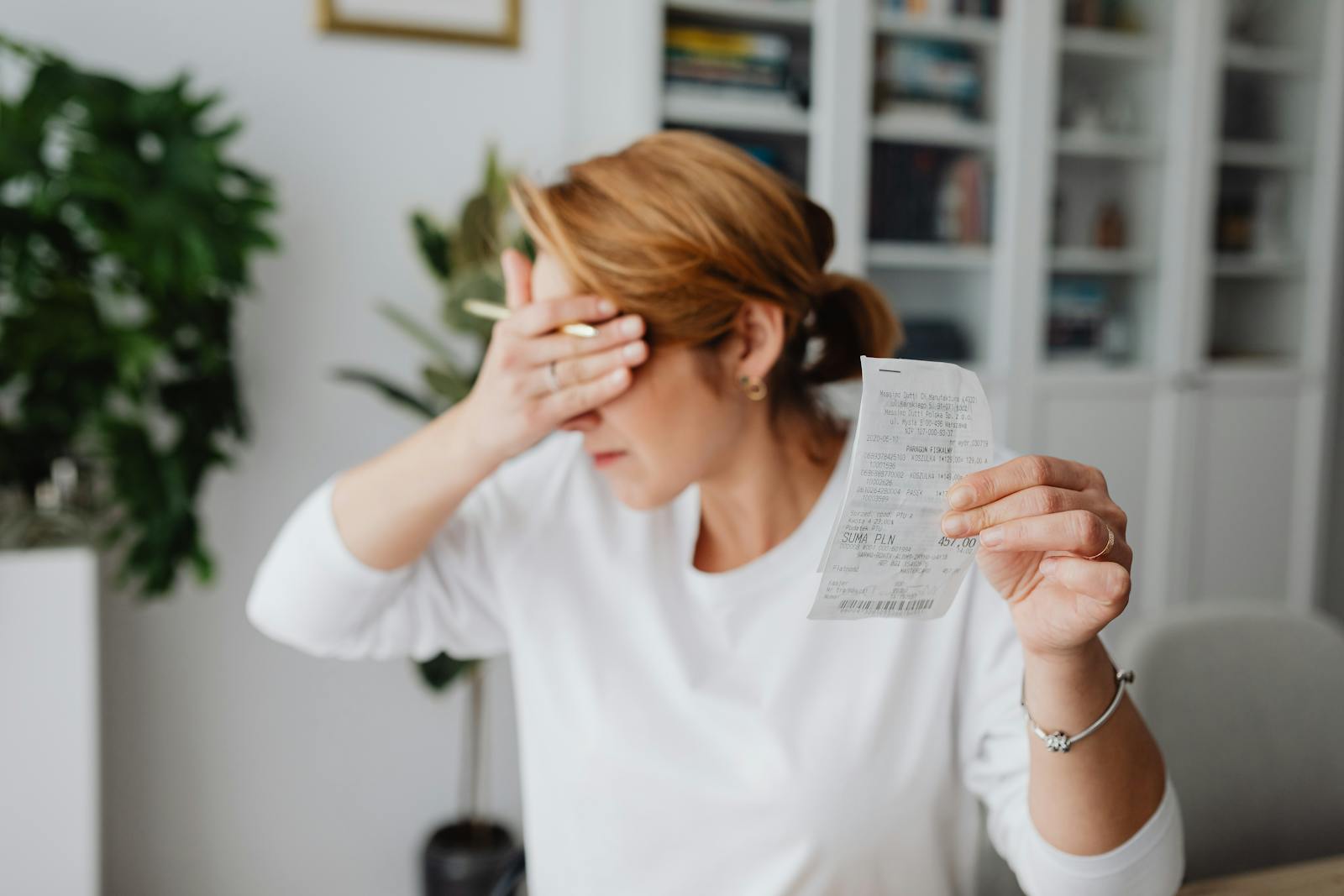 Woman experiencing stress while reviewing household expenses at home.