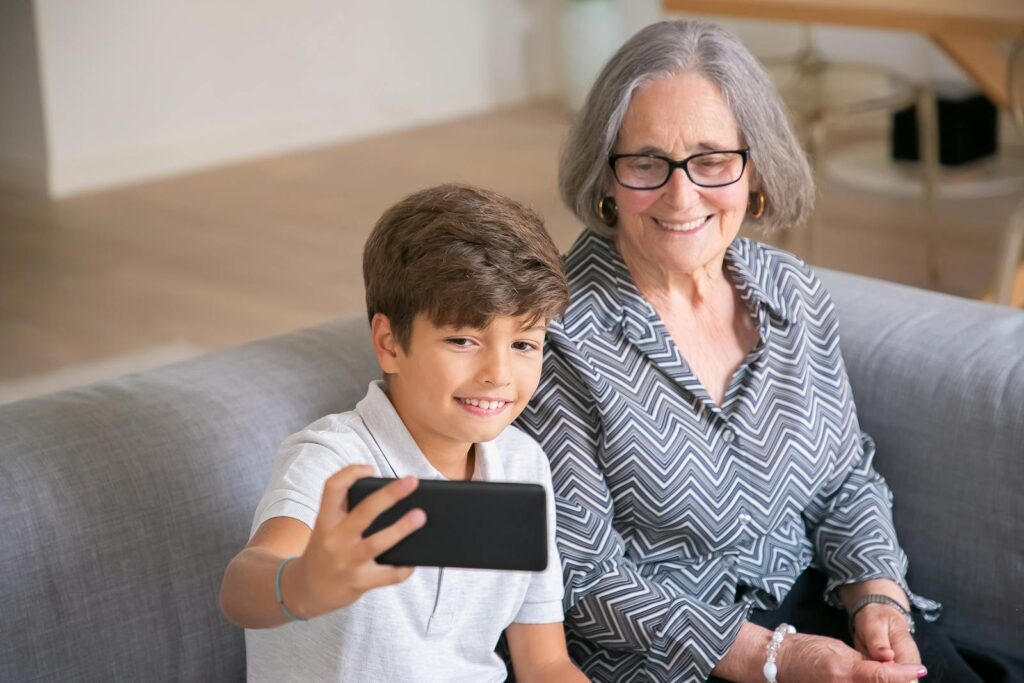 A joyful moment of a grandmother and her grandson taking a selfie together at home.