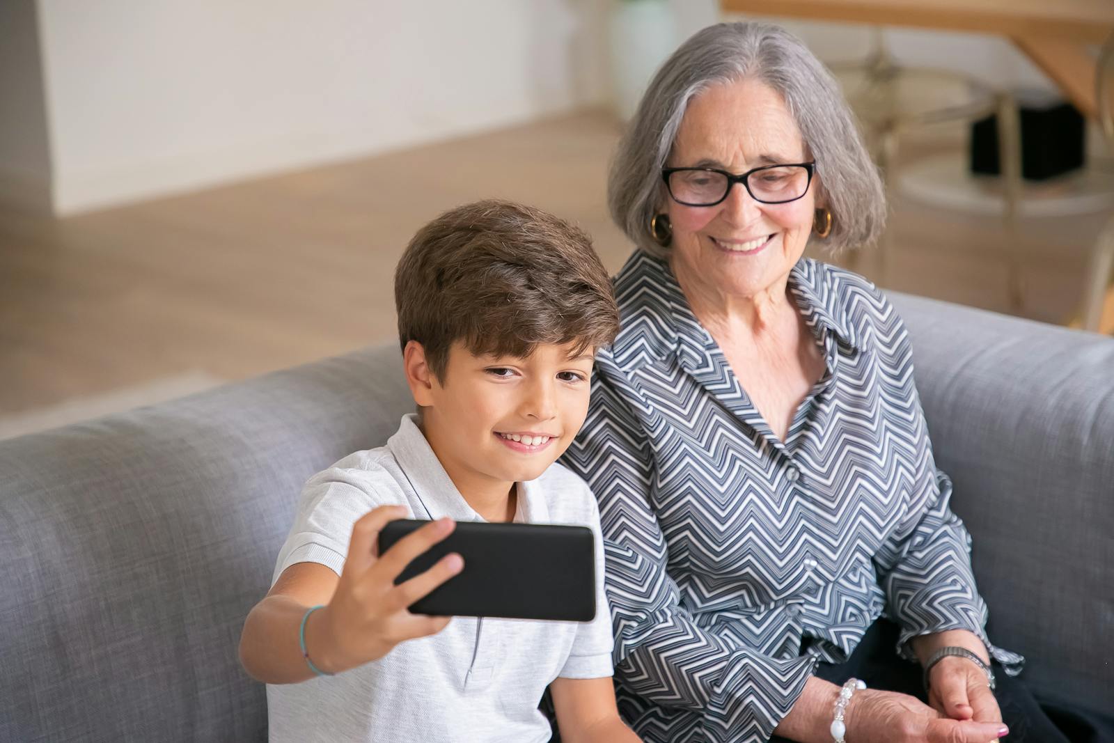 A joyful moment of a grandmother and her grandson taking a selfie together at home.