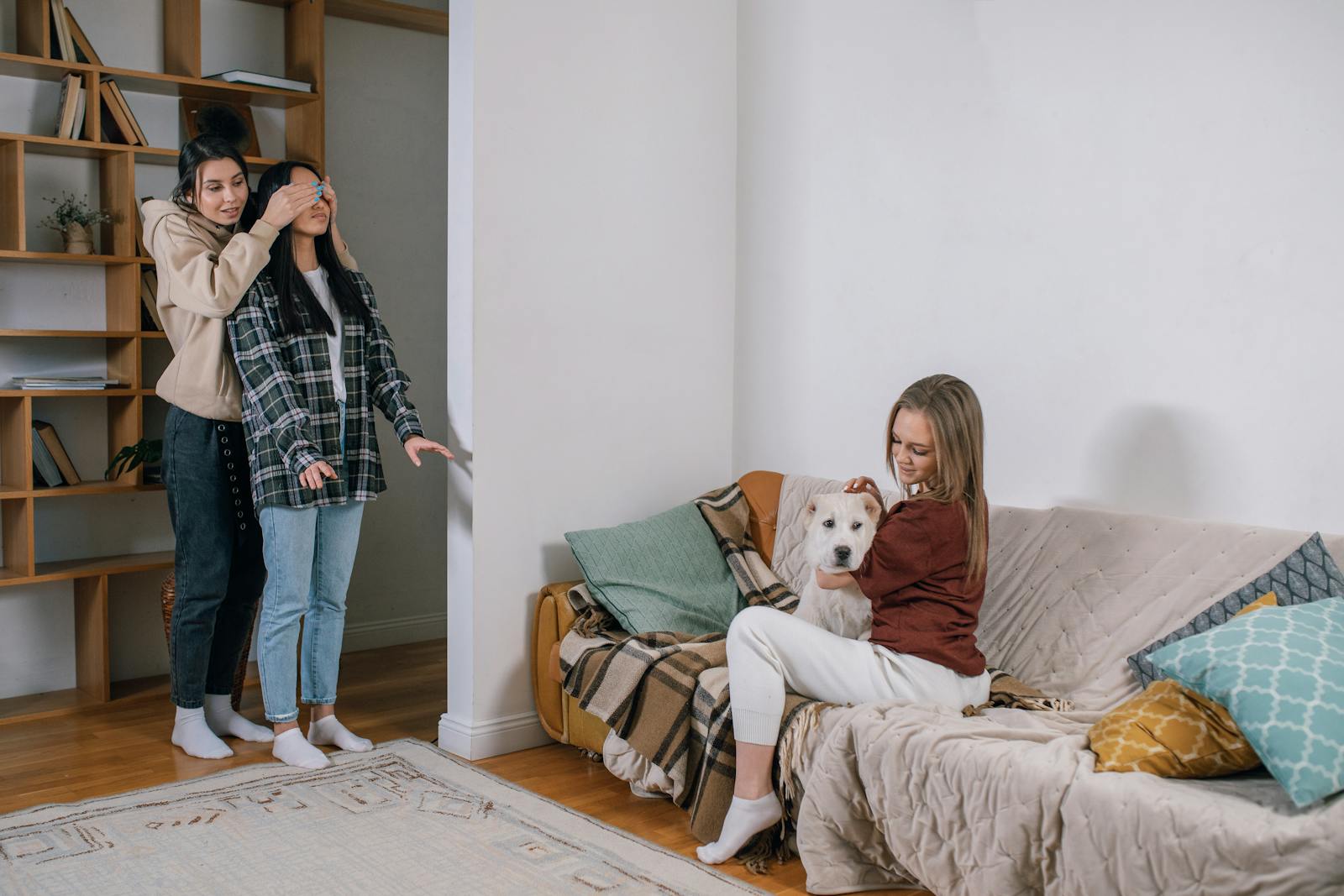 Three women share a joyful moment with a surprise gift—a cute dog, creating a heartwarming scene.