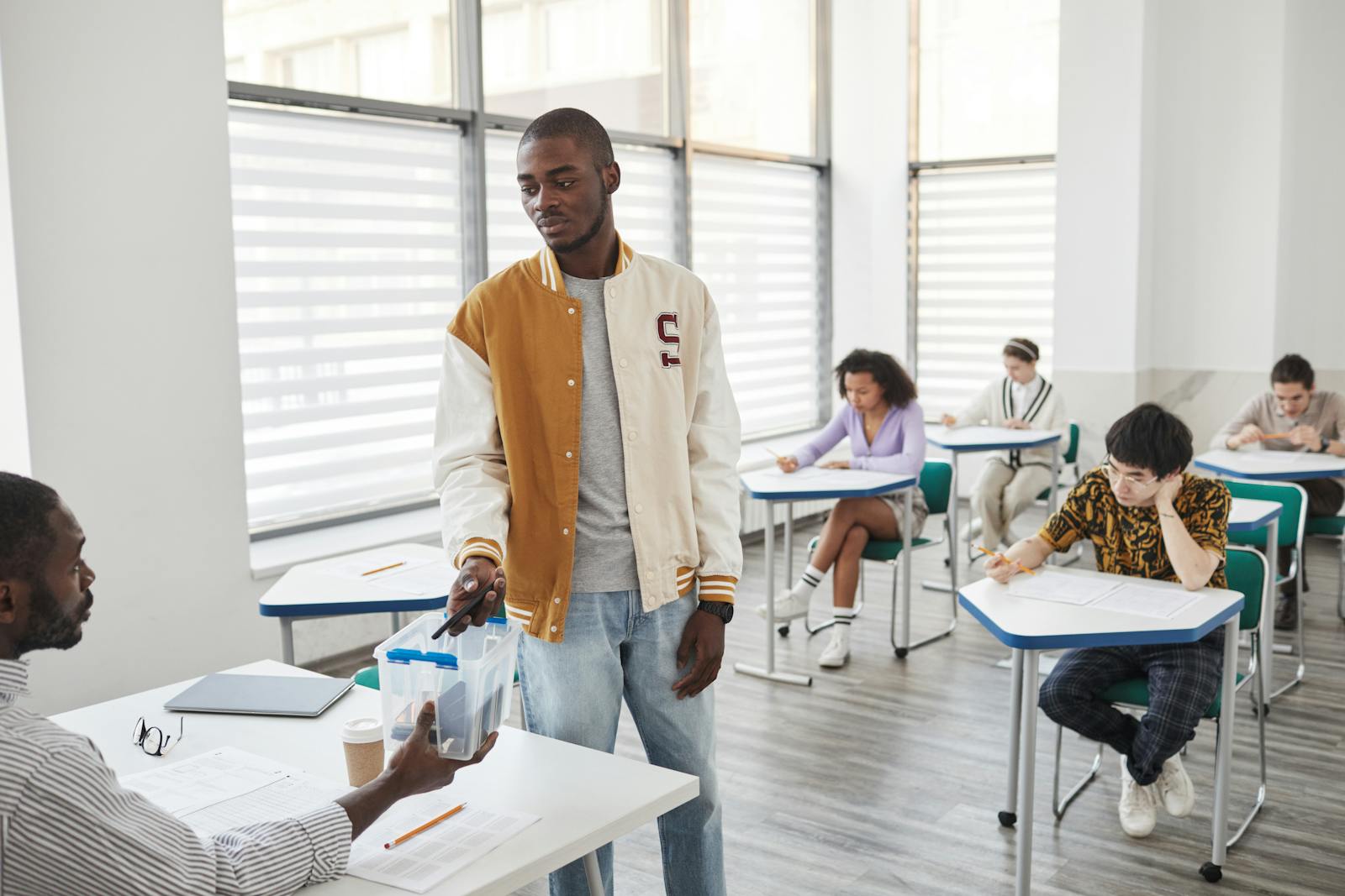 Group of students taking exams in a modern classroom setting.