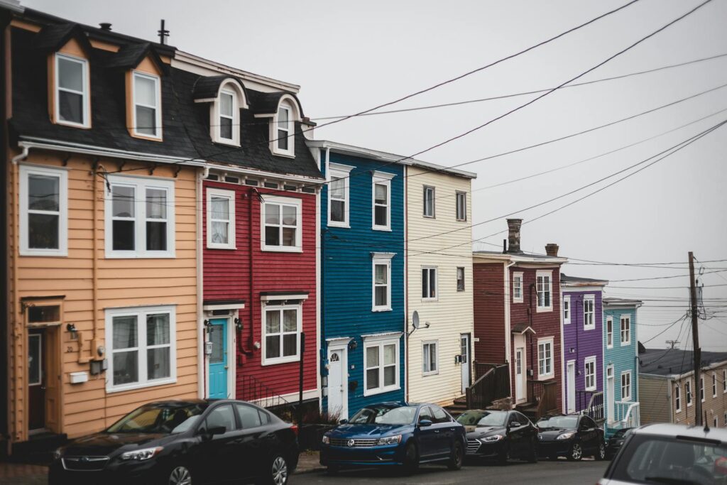 Vividly painted row houses lining a steep street with parked cars and overcast sky.