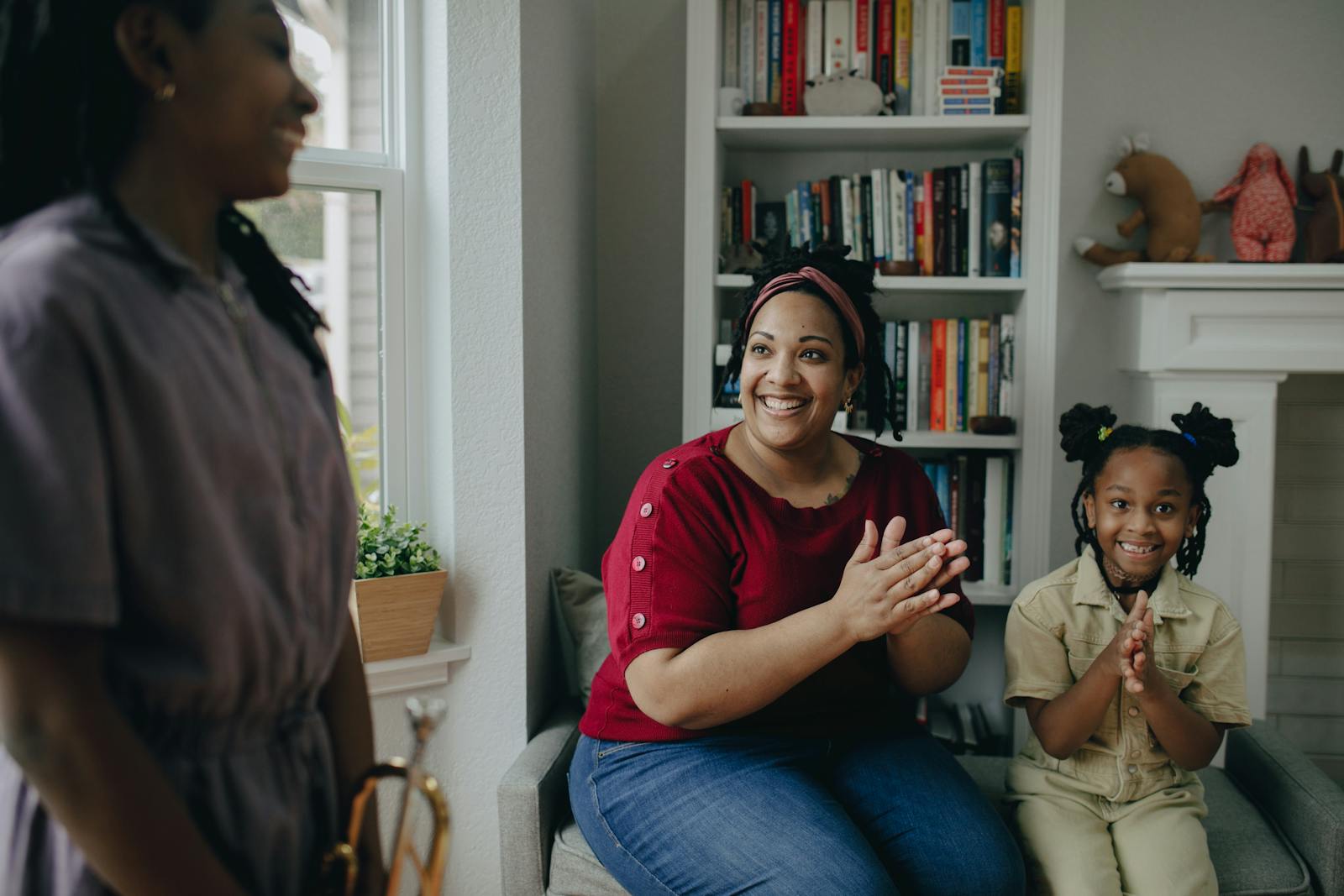 Mother and children clapping and smiling indoors, fostering happiness and connection.