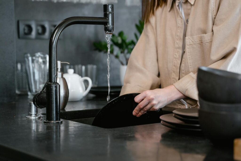 Close-up of a person washing dishes in a modern kitchen, emphasizing daily chores and routines.
