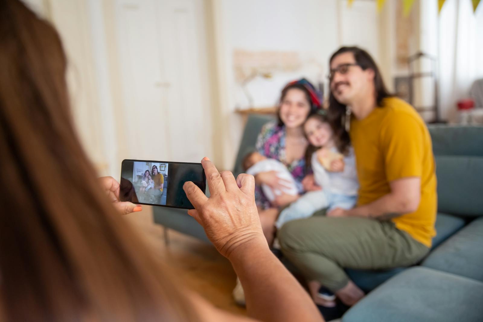 A family poses for a smartphone photo indoors, capturing a joyful moment together.