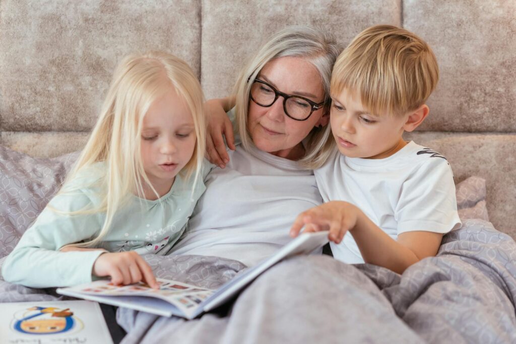 Loving grandmother reading a book with her grandchildren in bed, enjoying family time indoors.