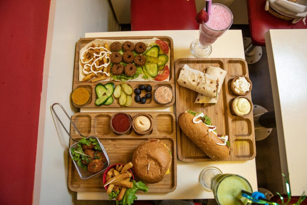 Delicious assorted fast food items including burgers, wraps, and fries on a wooden tray.
