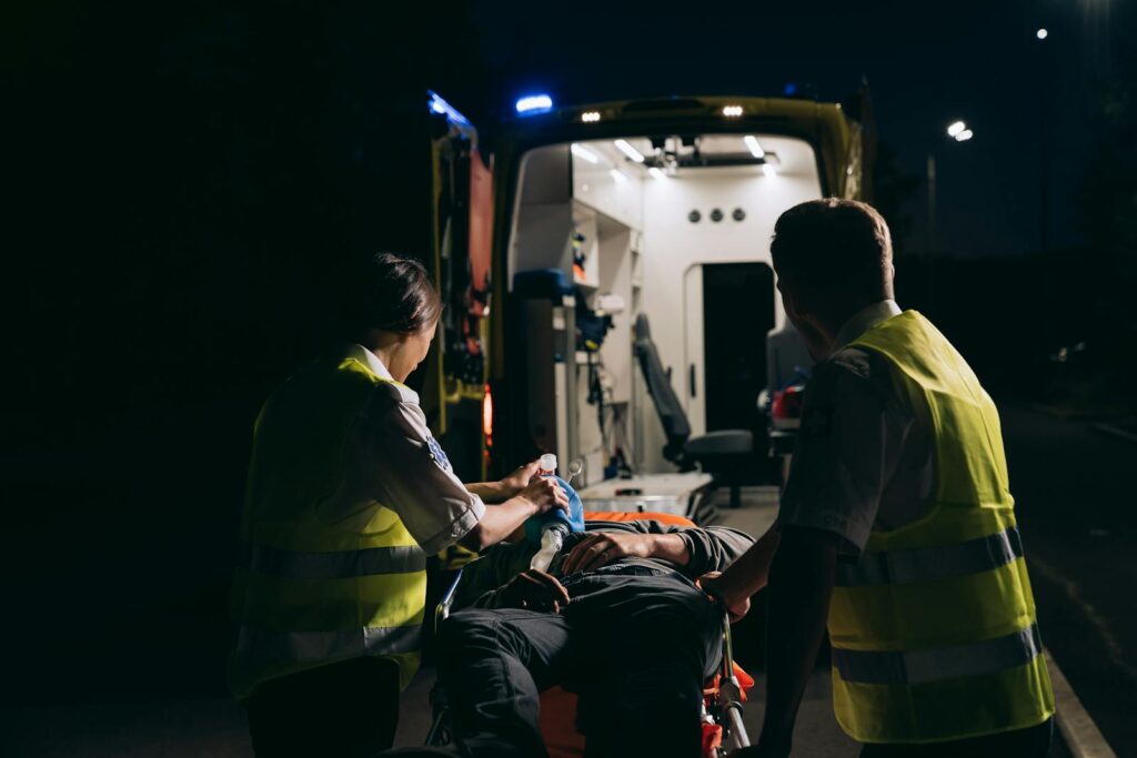 Paramedics aid patient into ambulance during night emergency.
