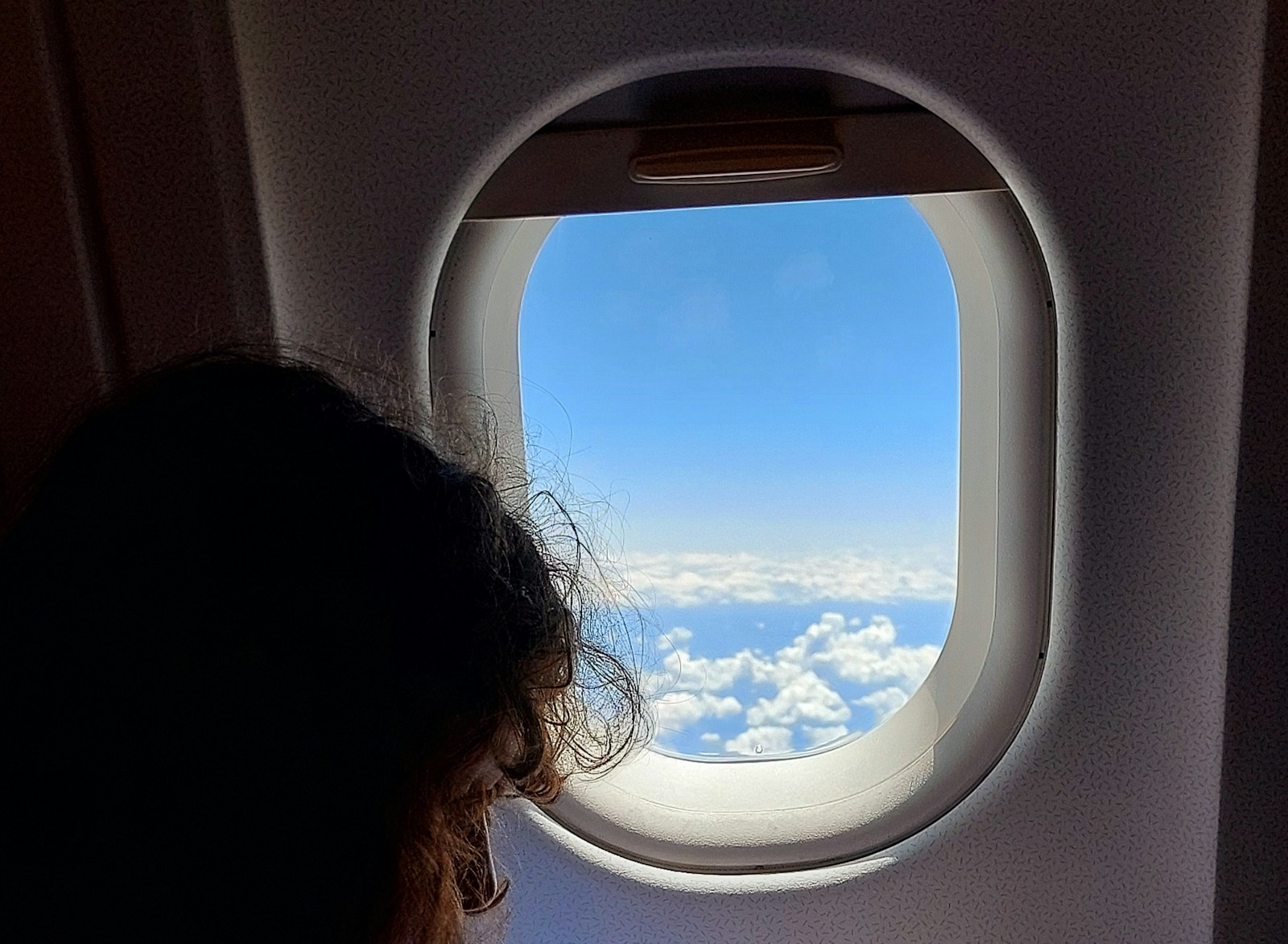 a woman looking out an airplane window at the clouds