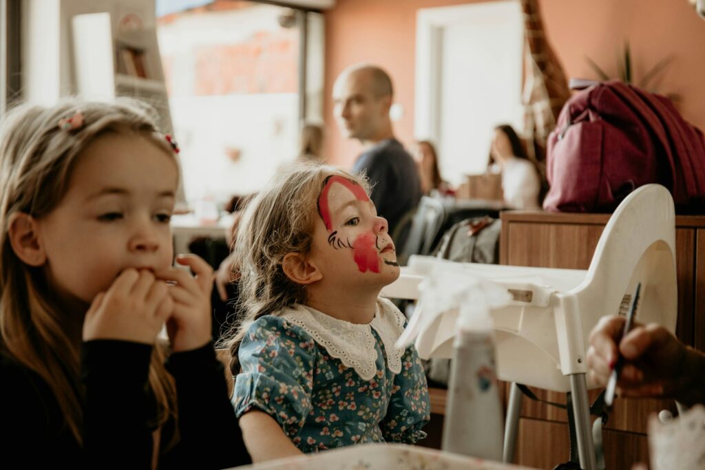 a couple of young girls sitting at a table with a paper and a pen in their mouth