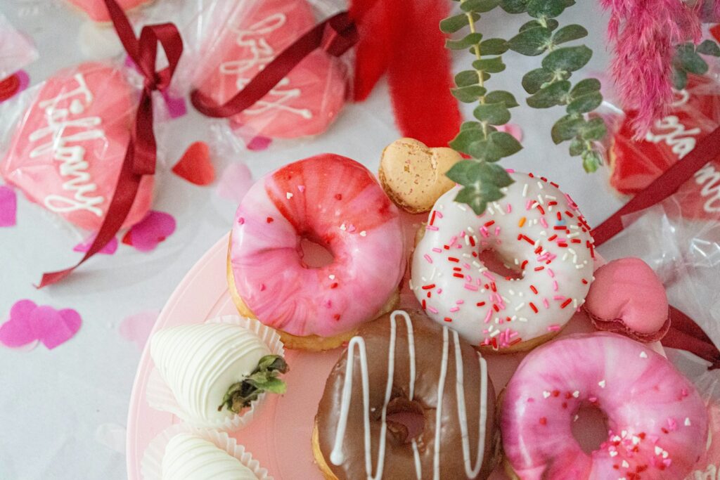 A pink plate topped with donuts covered in frosting