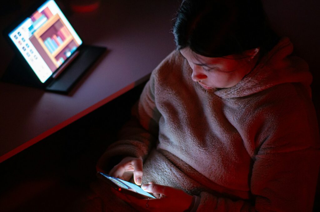A person sitting in a chair looking at a cell phone