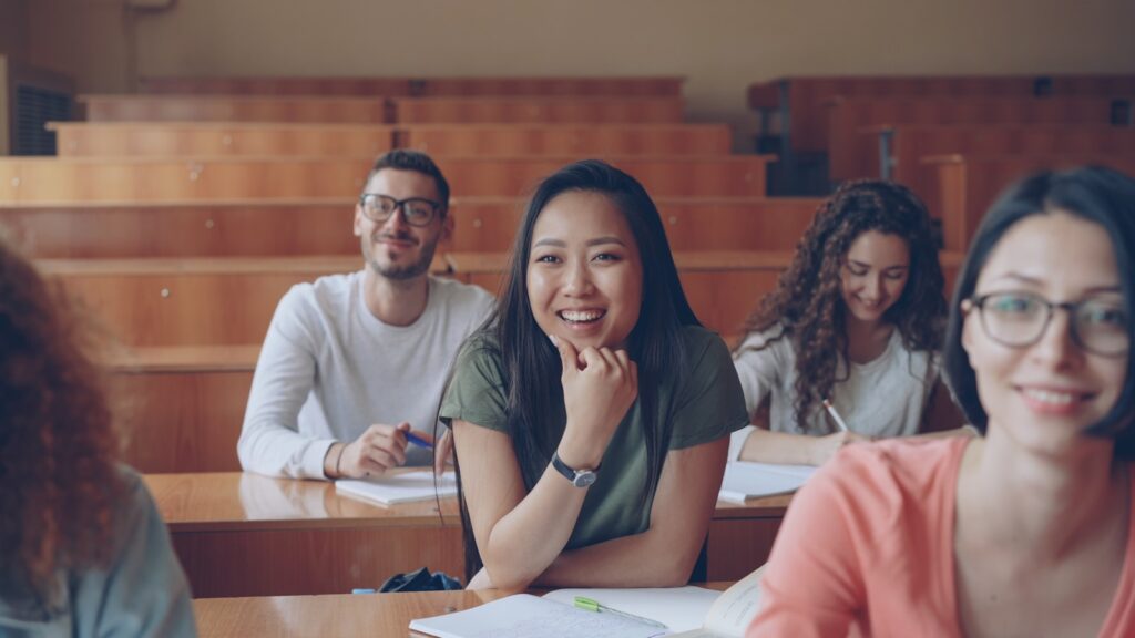 Students smiling in a lecture hall classroom.