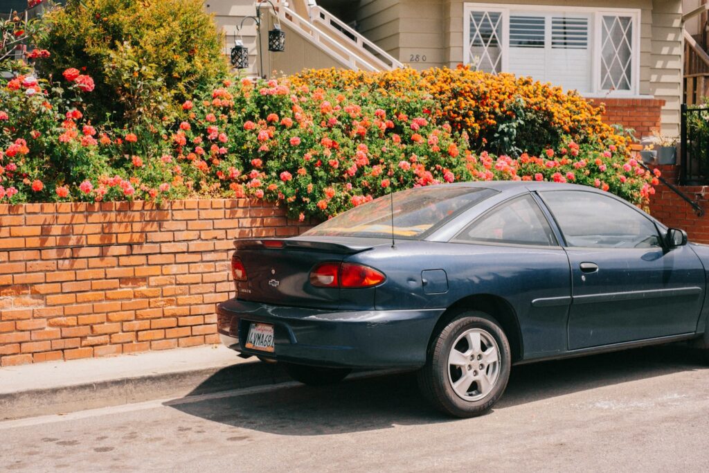 a car parked in front of a house with flowers on the side