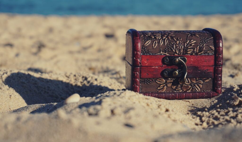 A decorative treasure chest sits on a sunny beach, invoking mystery and adventure.