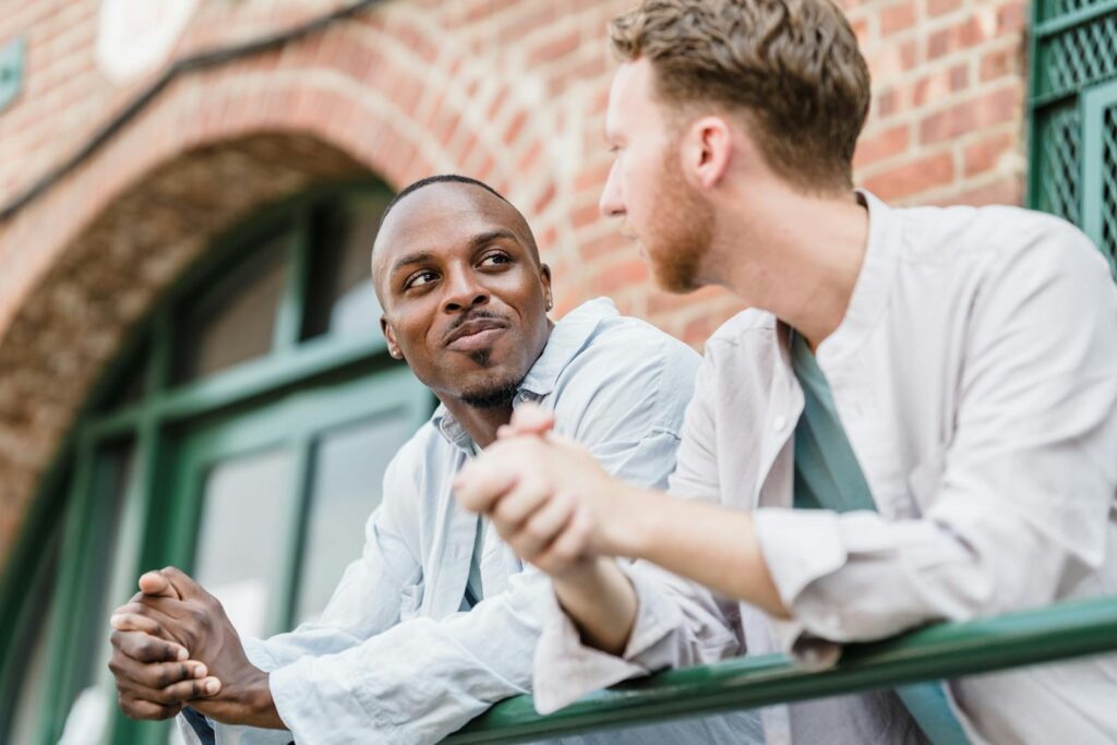 Two men smiling and talking outdoors, showcasing friendship and togetherness.