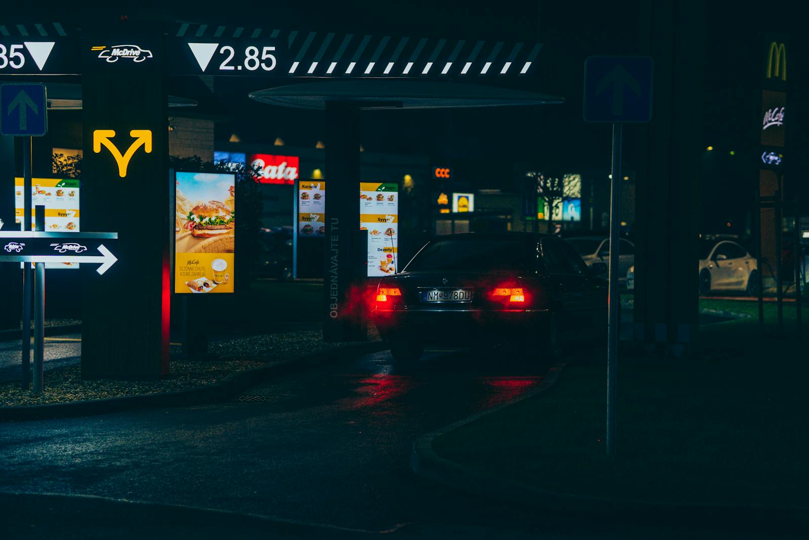Car navigating a McDonald's drive-thru at night, showcasing urban dining atmosphere.