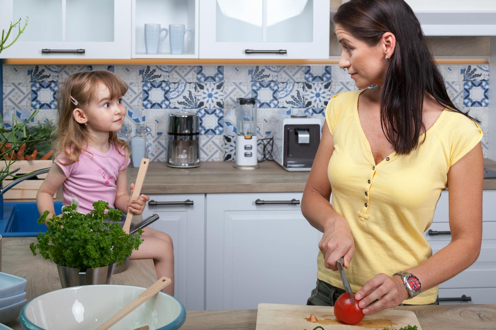 A mother and daughter enjoy cooking together in a cozy modern kitchen, fostering family bonds.