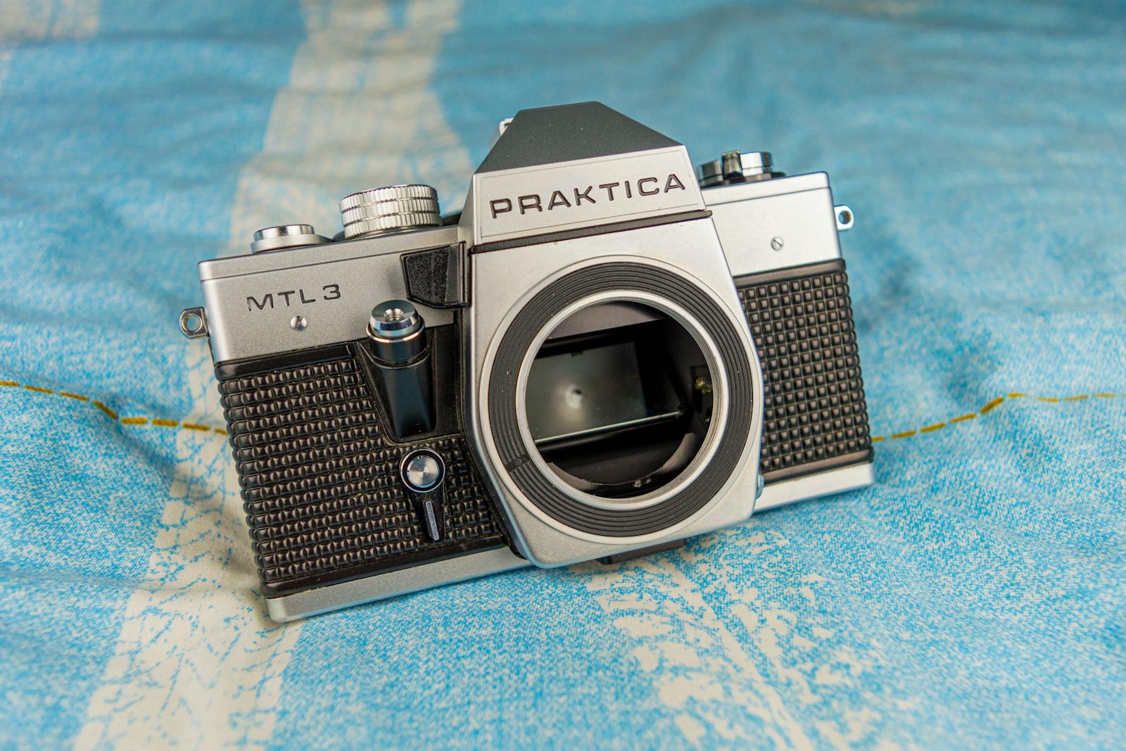Classic Praktica MTL3 film camera placed on a textured blue surface, showcasing retro design.
