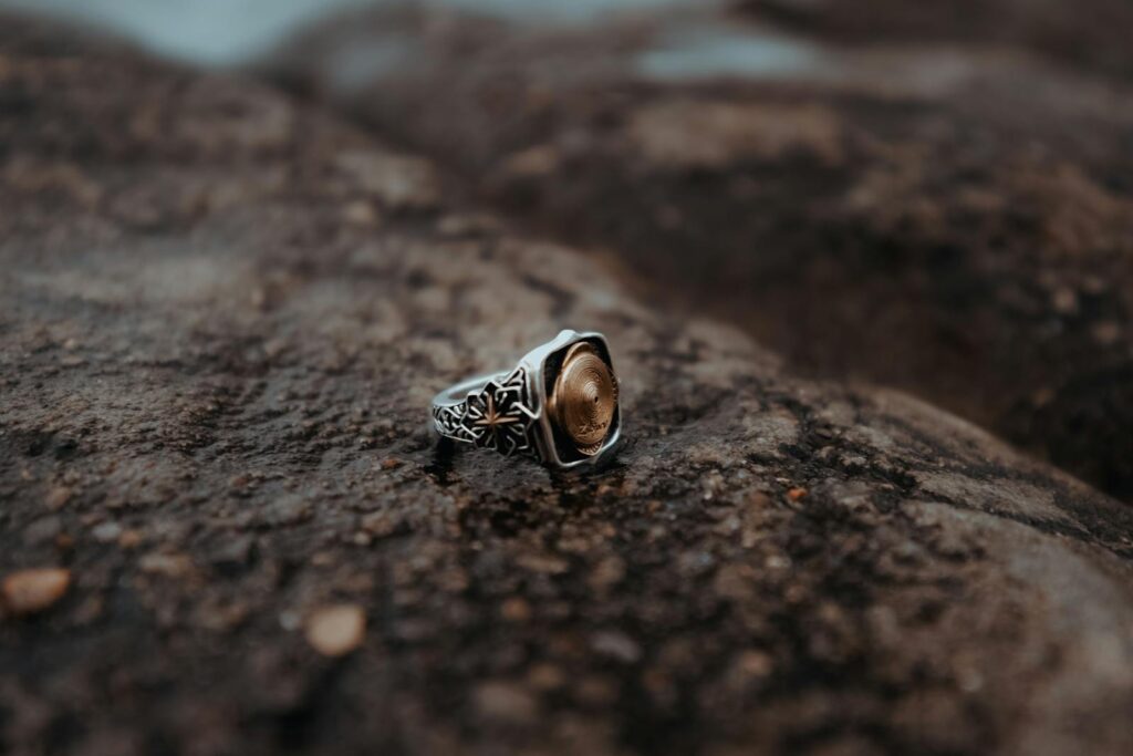 An ornate, antique ring rests on a rugged rock surface, showcasing intricate design details.