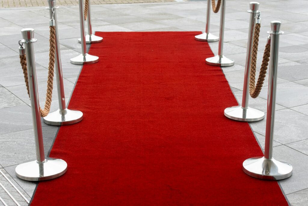 Red carpet entrance with stanchions on a tiled outdoor surface, perfect for events.