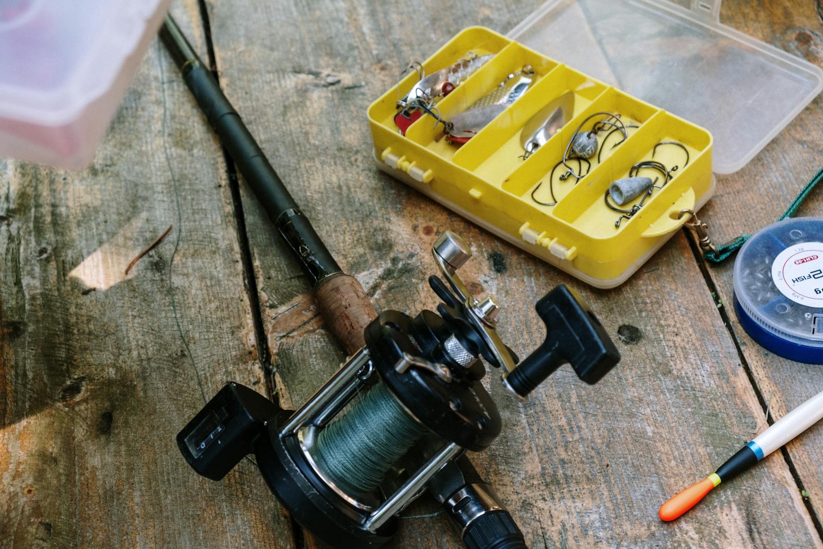 Close-up of fishing gear, including rod, reel, and lures on a wooden surface.