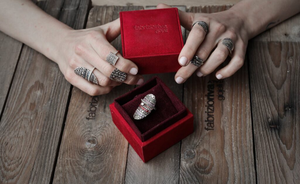 Elegant rings in a red velvet box displayed on a wooden table, showcasing luxury and style.