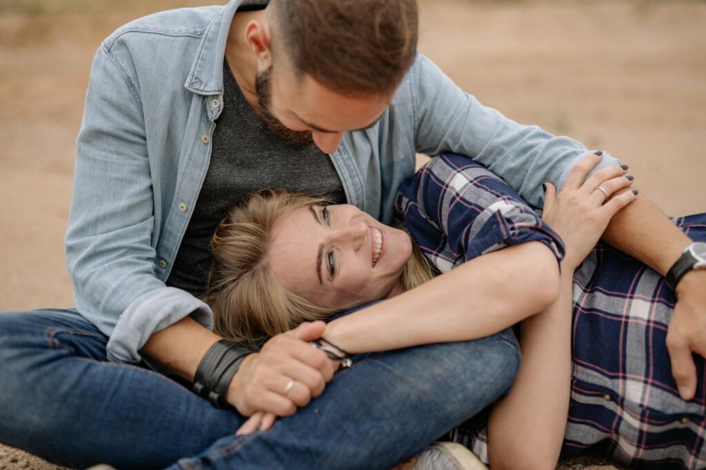 A loving couple embraces outdoors, smiling and relaxed in casual attire, depicting affection and happiness.