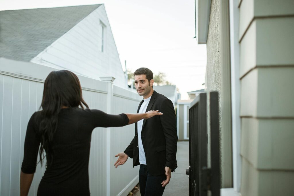 Man and woman having an argument in a suburban alleyway during the day.