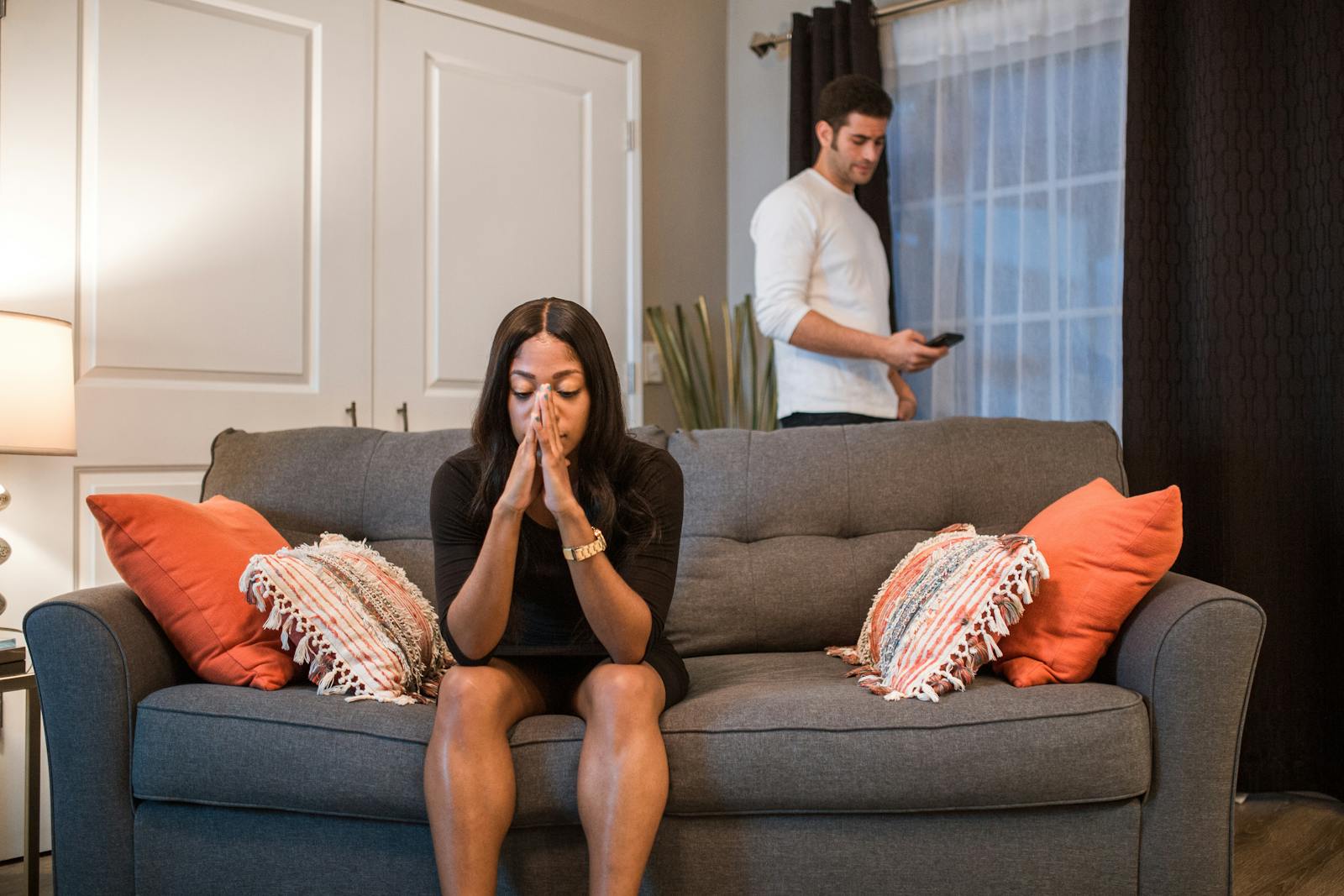 A man and woman experiencing emotional turmoil and separation in a living room setting.