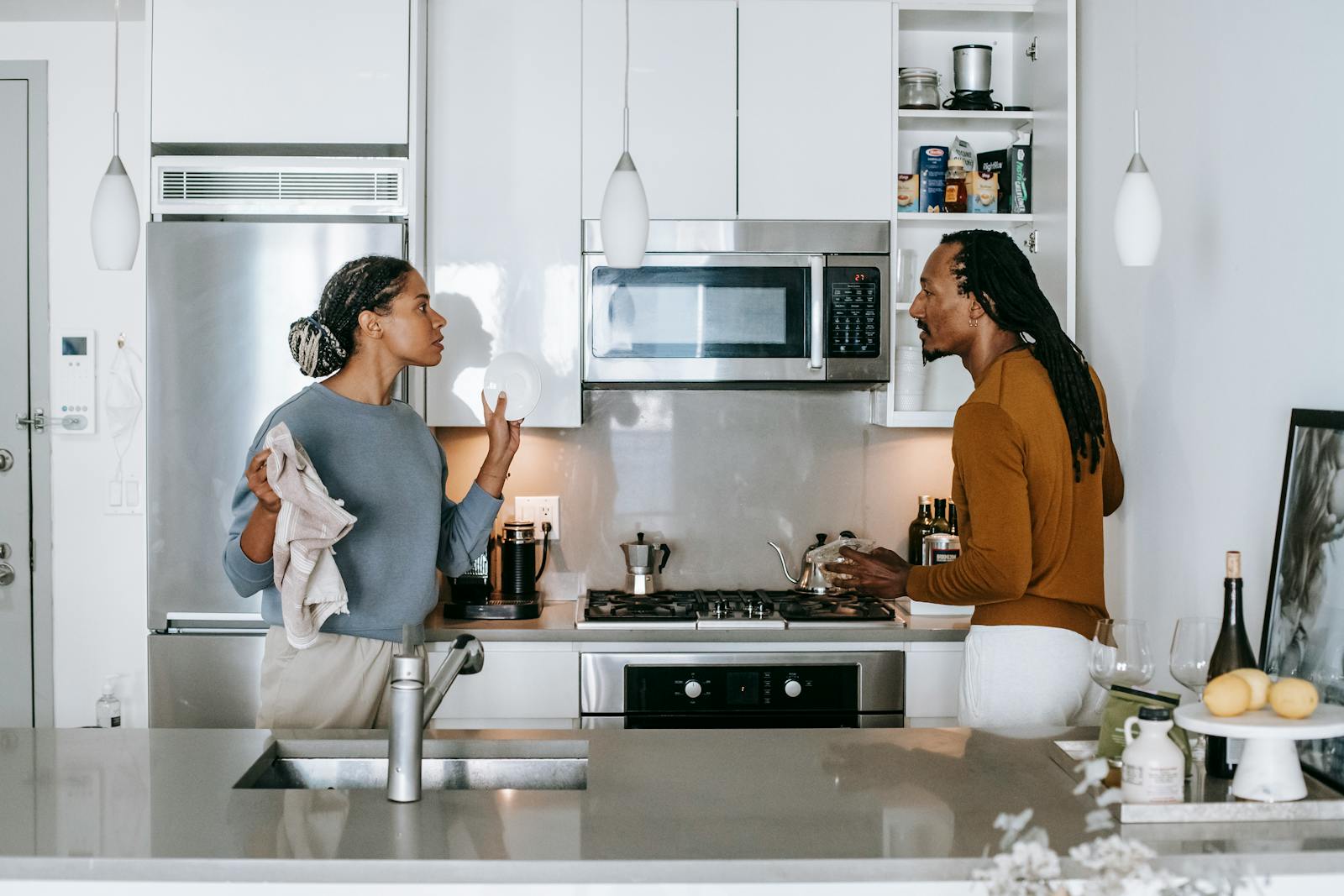 A couple engaged in a serious discussion in a modern kitchen setting.