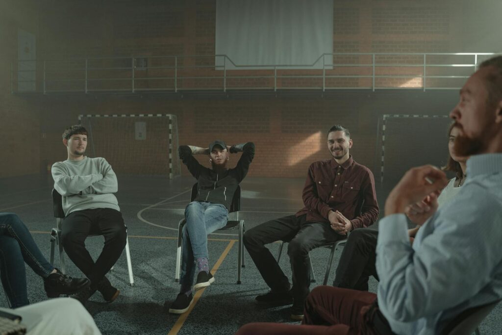 A group of adults engaging in a therapy session in a spacious gymnasium setting.