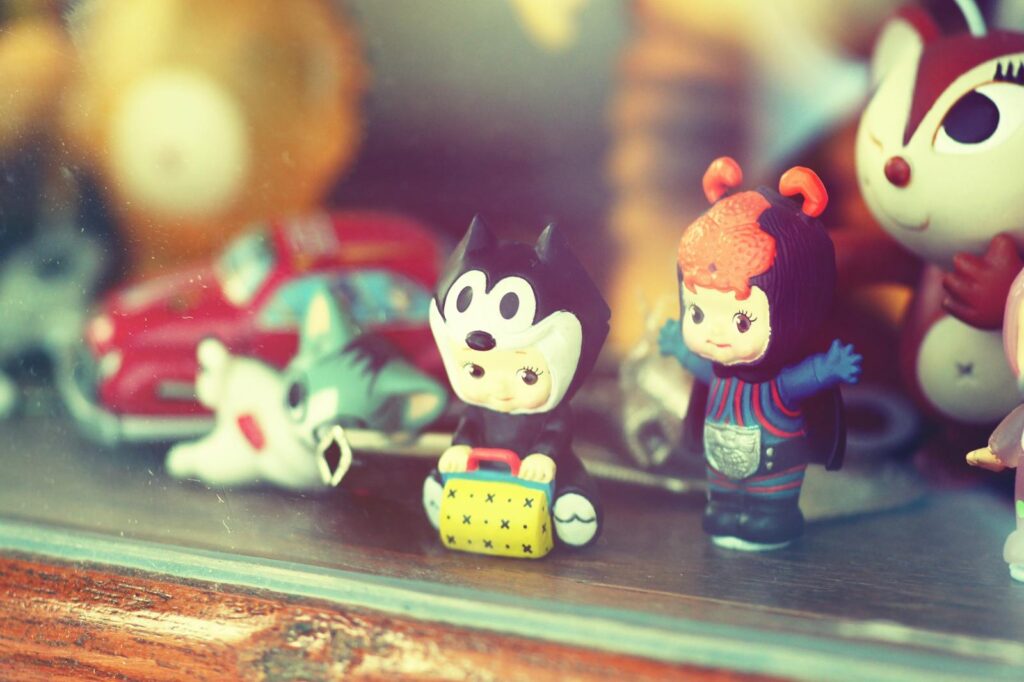 Close-up of vintage toy figurines on a wooden shelf inside a glass display case.