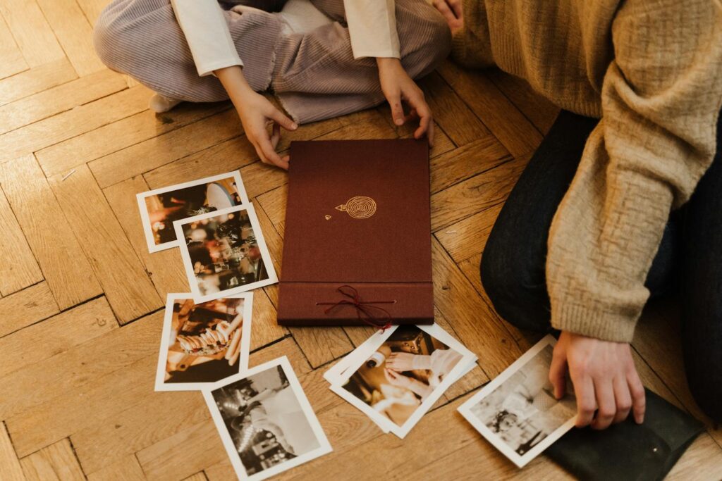 Top view of two people reminiscing over a photo album indoors.