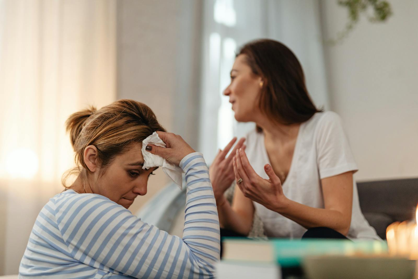 Two women in a thoughtful conversation indoors, one looks distressed.