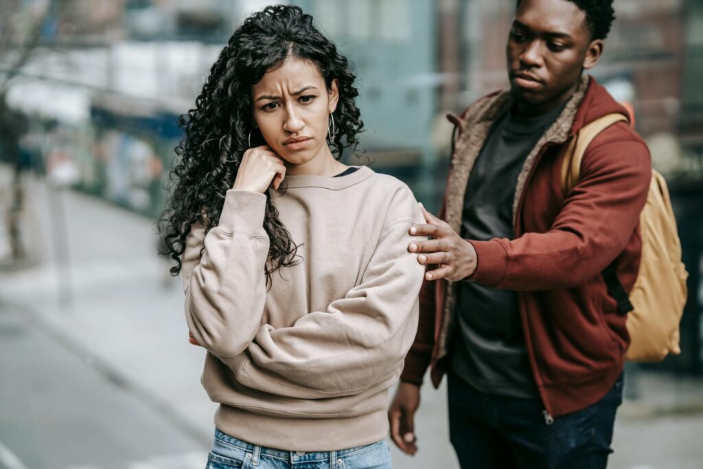 A young couple having a disagreement outdoors, displaying emotions and tension.
