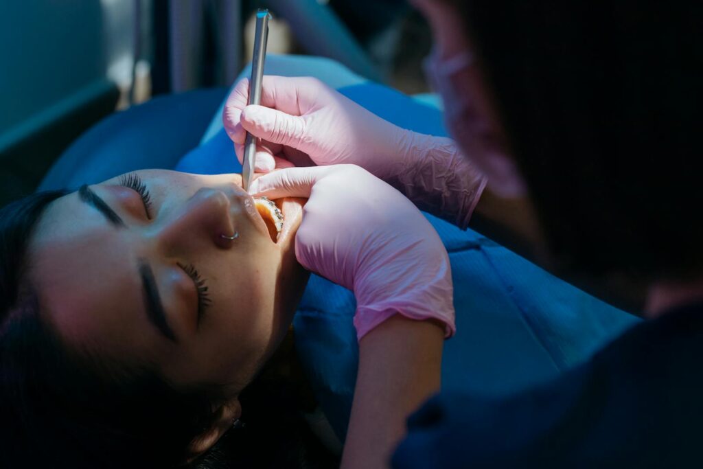 Dentist examines patient during a dental procedure with precision tools.