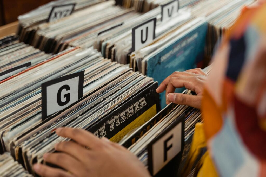 Person searching through labeled vinyl records in a store, capturing the essence of nostalgia and music.