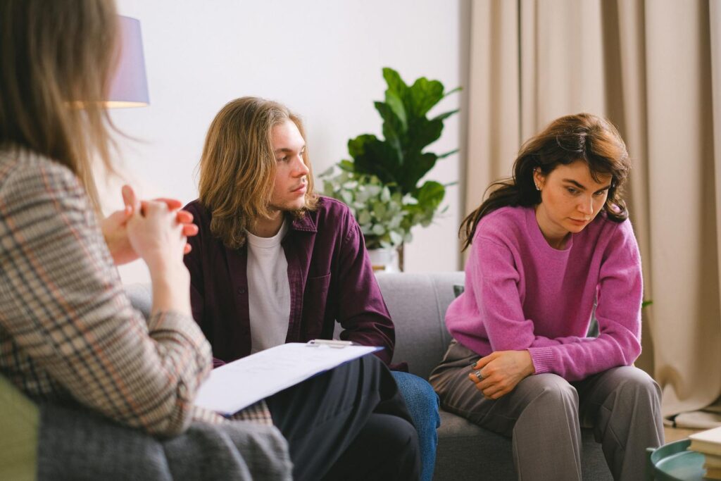 A couple engaged in a therapy session with a psychotherapist, discussing and reflecting indoors.