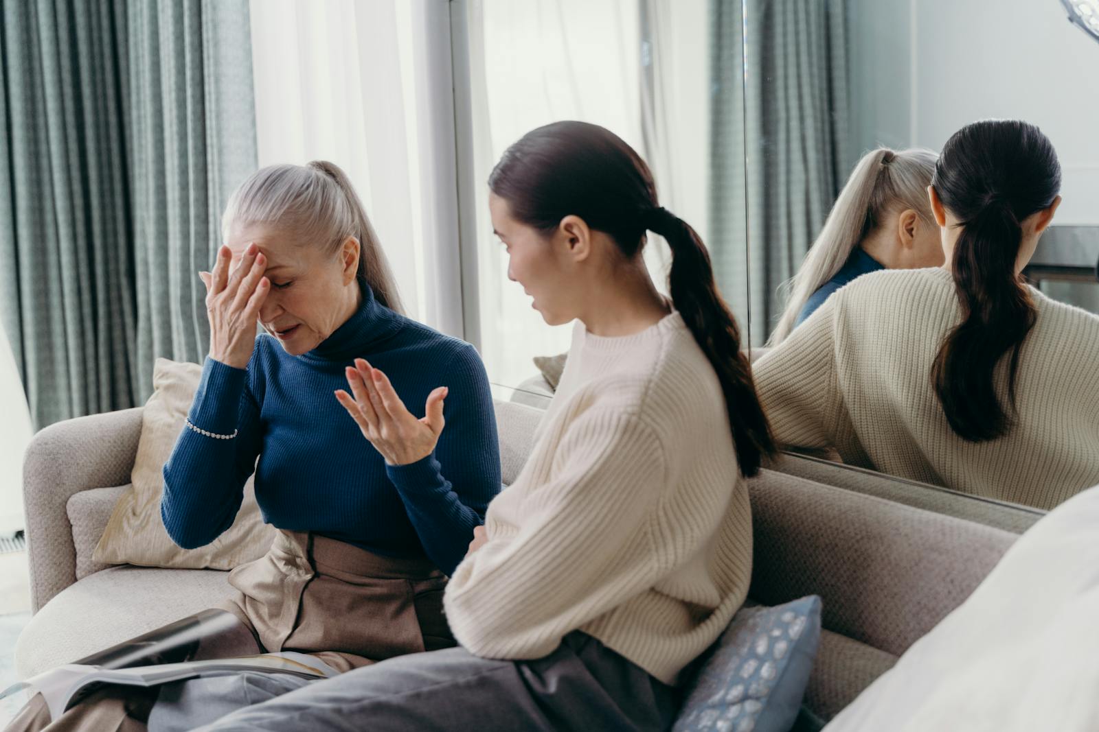 A touching moment of bonding between a mother and daughter sitting on a couch indoors.