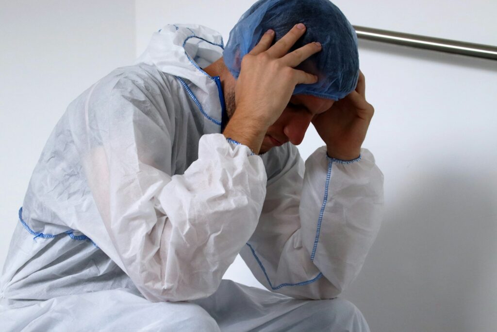 man in white dress shirt and blue pants covering his face with blue textile