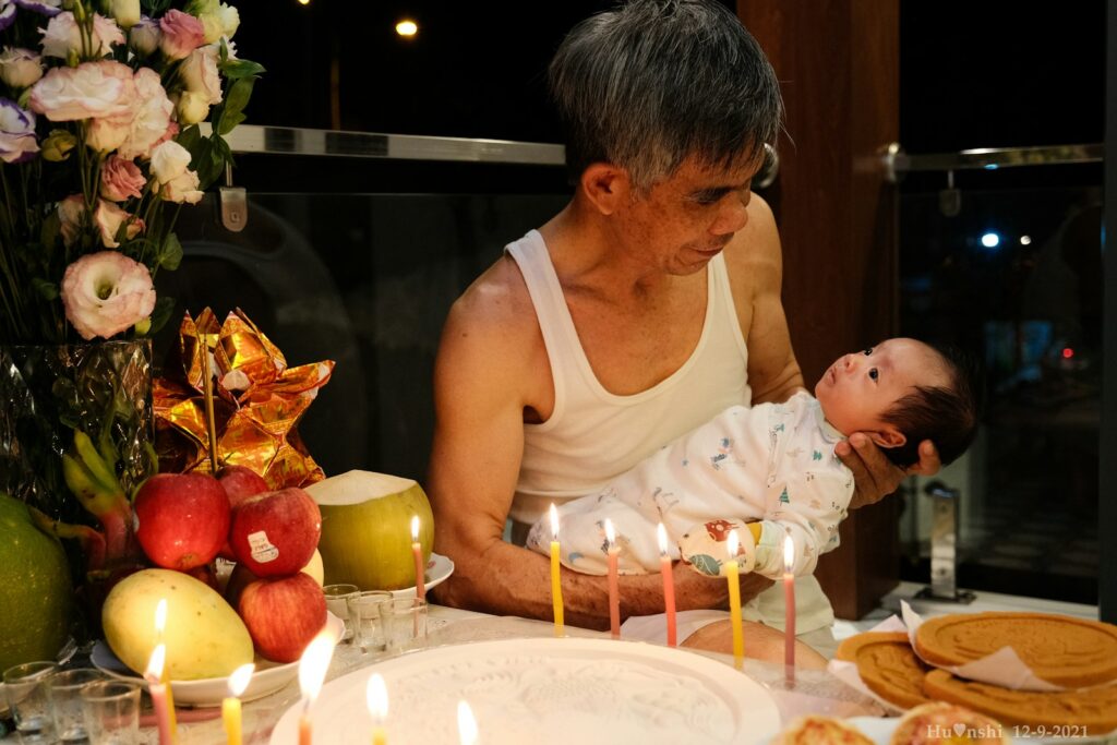 a man holding a baby in front of a cake with lit candles